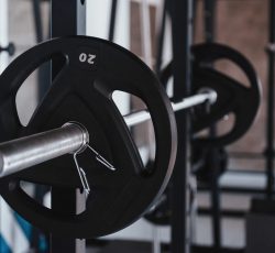 Conception of strength. Black barbell on the metal stand in the gym at daytime. No people around.